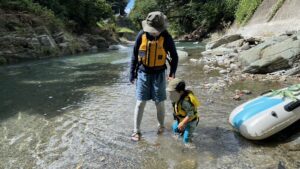 浅瀬で足元を見る親子。子どもの基準で深さを測る